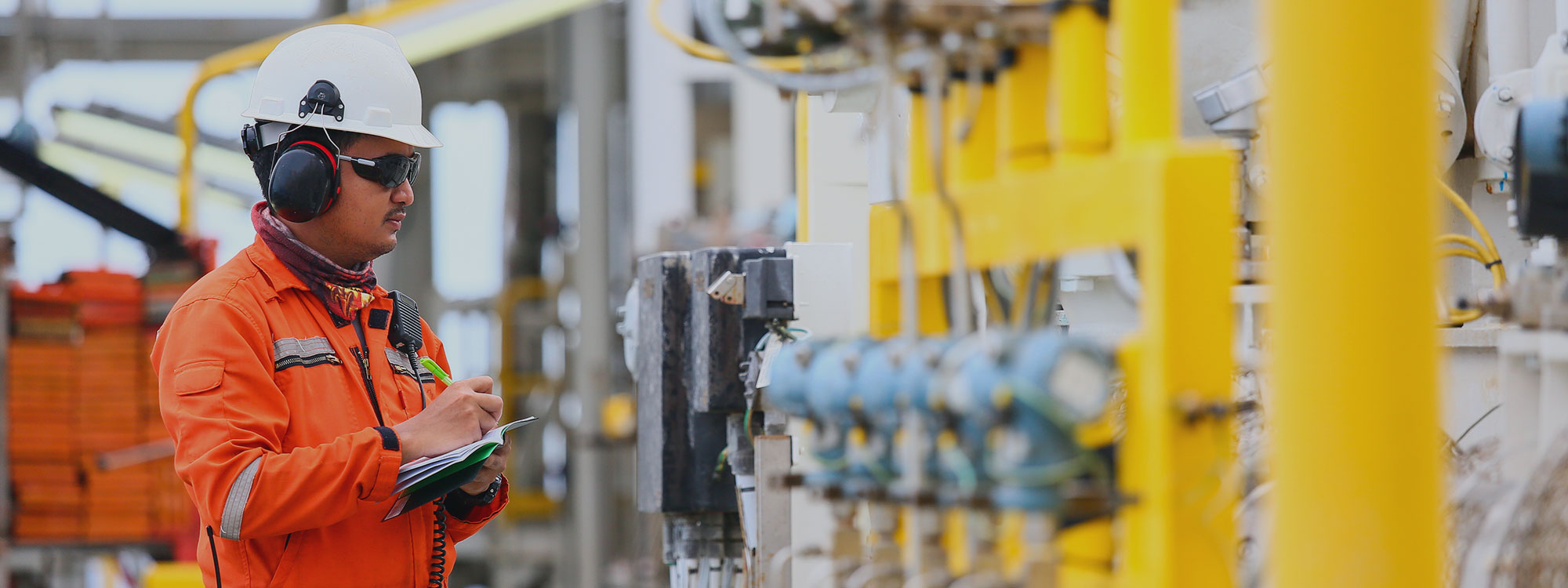 Image of man with hardhat inspecting machinery. 