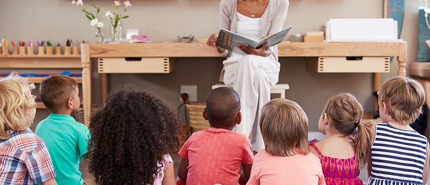 Photo of adult reading to a group of captivated children.