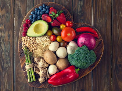 Healthy food on a heart shape cutting board. Love of food concept with fruit, vegetables, grains and high fibre foods. Rustic wood textures