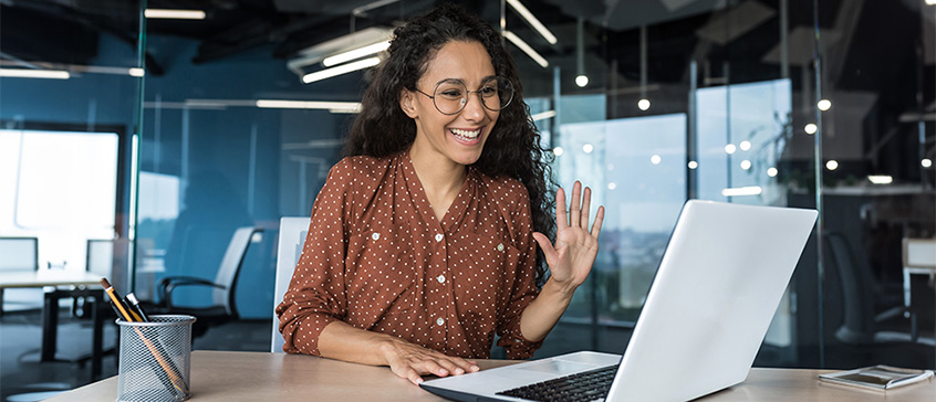 Photo of graduate student waving at laptop. 