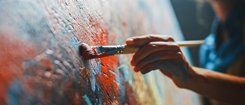 Female artist works on abstract oil painting, Moving paint brush energetically she creates modern masterpiece.