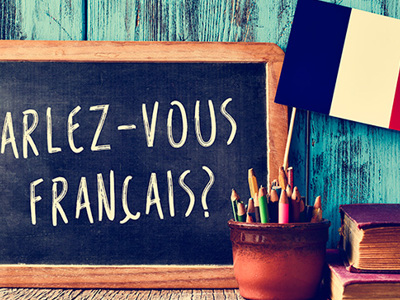 Desk with a French flag, headphones resting on books, a potted plant, colorful sticky notes and pencils, and a blue sign reading