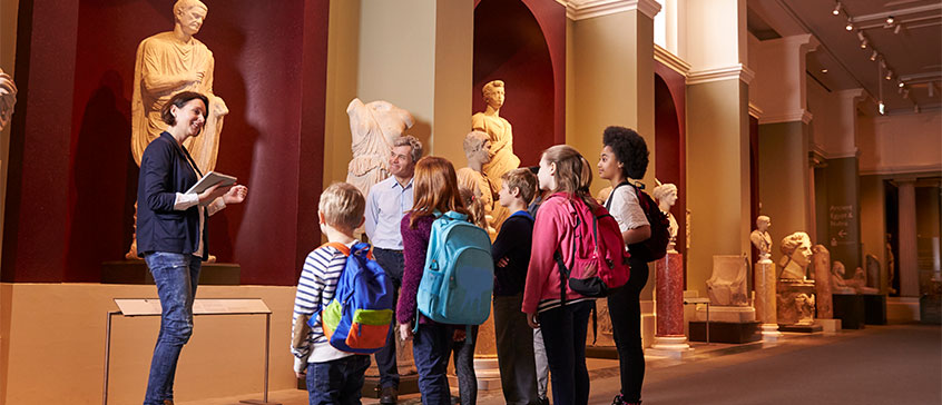 Photo of curator giving tour of museum to children.