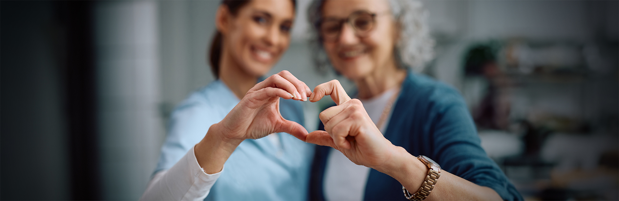 Nurse and senior holding hands to form the shape of a heart. 