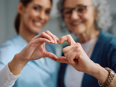 Nurse and senior putting hands together in the shape of a heart