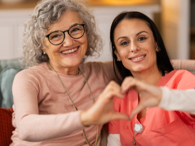 Nurse and senior forming hands into a heart shape