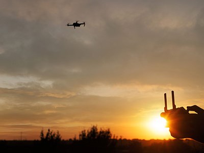 A drone flying in the sky at sunset