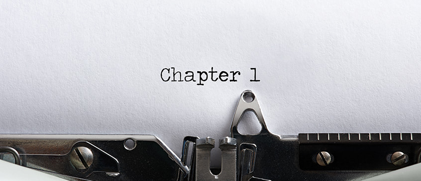 Close-up of a vintage typewriter with white paper inserted, showing Chapter 1 typed at the top of the page, representing the beginning of the novel writing process.