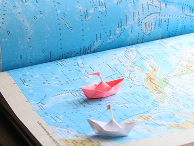 Miniature paper ships on an atlas