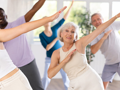 Group of people performing gentle stretching exercises in a bright studio, symbolizing movement-based strategies for managing chronic pain and improving mobility.
