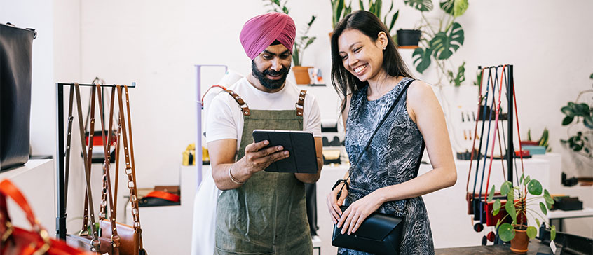 Punjabi man with a turban talking to a woman in a store. 