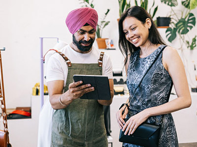 Punjabi man with a turban talking to a woman in a store. 