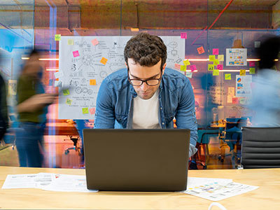 Marketing office worker at laptop in a busy modern office