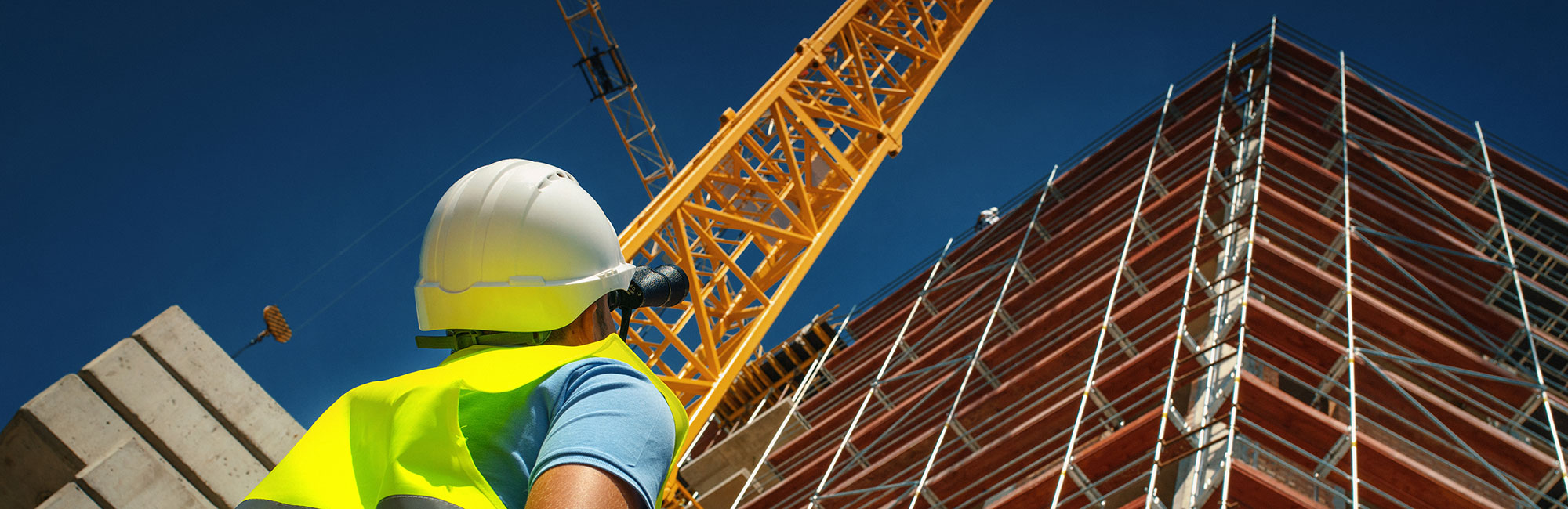 Person in hard hat looking up at tall building being built