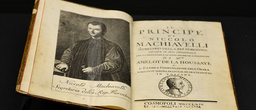 Open antique book showing the title page of Machiavelli’s ‘The Prince’ alongside an engraved portrait, symbolizing historical study of political power and strategy.