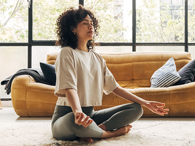 Young multiracial latina woman meditating at home in a comfortable, naturally-lighted living room