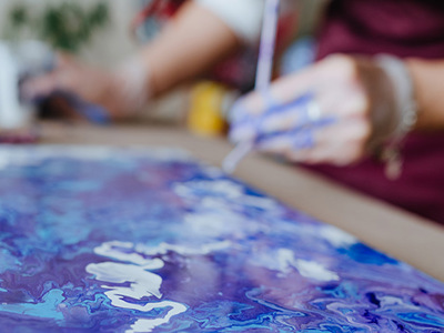 Close-up of fluid acrylic paint in vibrant purple and blue tones spreading organically across canvas, with artist