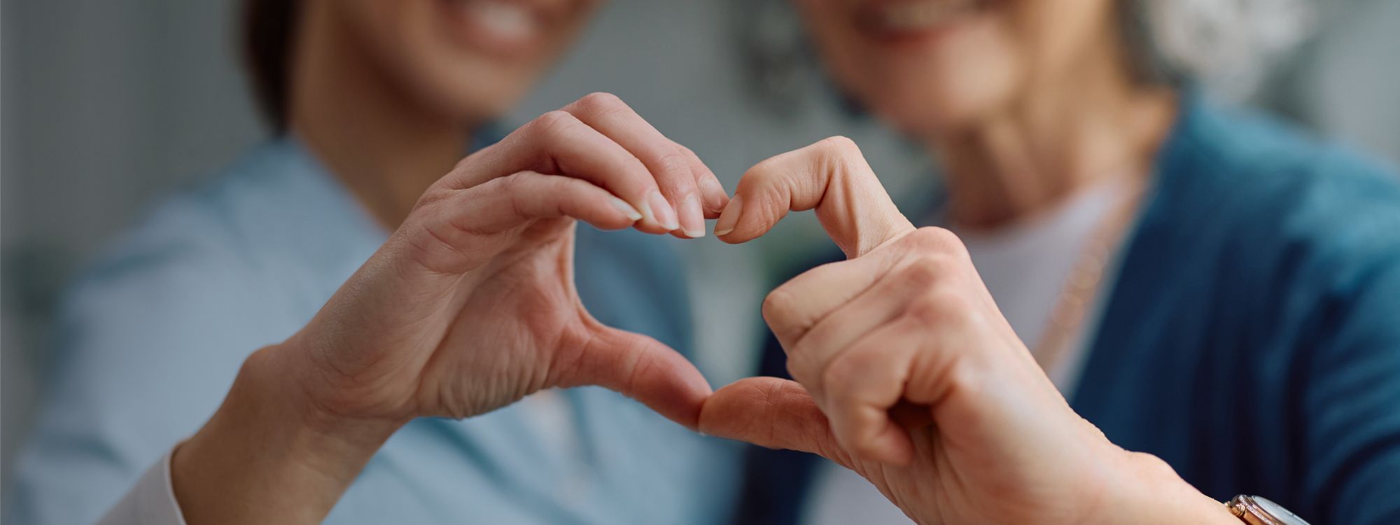 Nurse and senior holding hands to form the shape of a heart.