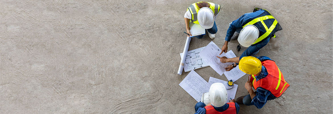 Birds eye view of four construction working looking at plans