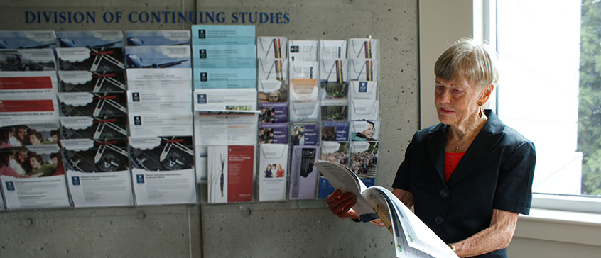 Photograph of Nan Walmsley looking at a course calendar. 