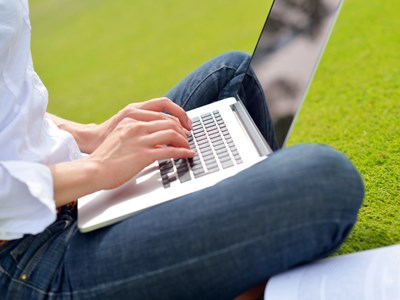 Photo of student working on laptop in a park