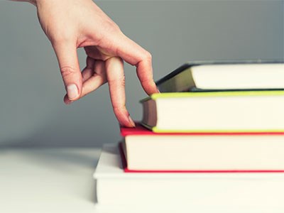 Picture of fingers climbing stairs made out of books